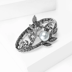Vintage floral brooch with grey pearl and dark diamonds on white geometric display stand