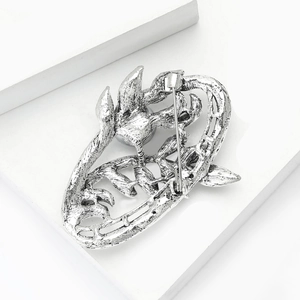 Detail of vintage silver brooch back featuring secure metal safety pin and aged texture