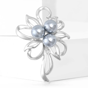 Detail of matte silver flower brooch with three grey pearls on a white display block