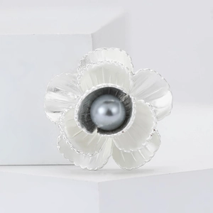 Macro di una spilla a camelia con petali in smalto bianco e perla grigio-blu al centro