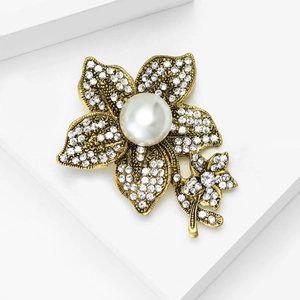 Close-up of vintage gold floral brooch with sparkling rhinestones and white pearls