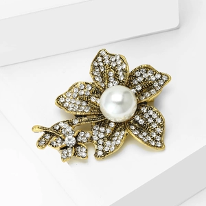 Detail of vintage flower brooch with central pearl and rhinestone-studded golden petals