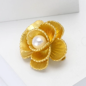 Elegante spilla a fiore in oro opaco con perla centrale su supporto geometrico bianco