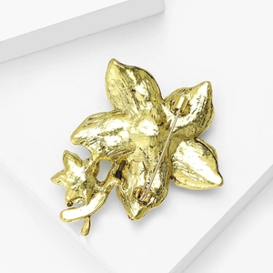 Macro shot of gold floral brooch back detail with secure safety pin clasp on white block