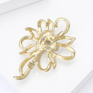 Detail of matte gold alloy flower brooch showing the textured back and secure safety pin
