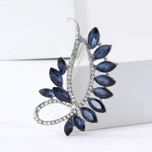 Elegant leaf brooch with navy blue crystals and sparkling white rhinestones on white block