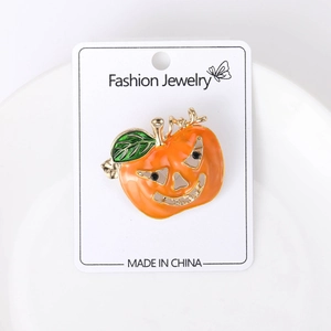 Détail d'une broche citrouille d'Halloween en émail orange avec finition dorée sur carte