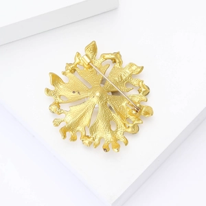 Close-up of the back of a matte gold flower brooch showing the pin clasp mechanism