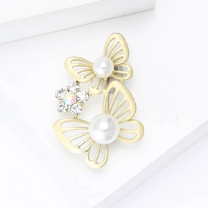 Broche papillon dorée élégante avec perles et strass sur fond géométrique blanc