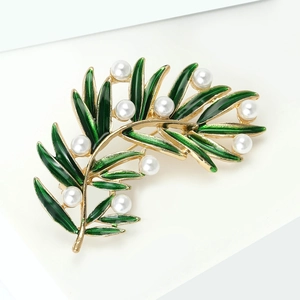 Détail macro d'une broche feuille verte avec placage d'or et perles blanches