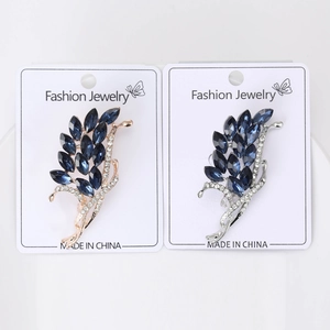 Detail of rose gold and silver feather brooches with dark blue stones and white crystals