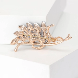 Elegant rose gold branch brooch with navy blue and clear crystals on a white pedestal