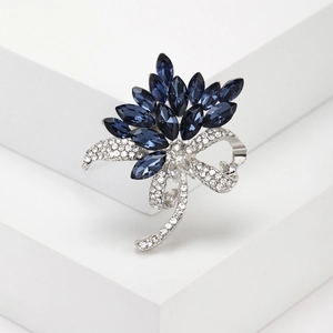 Silver flower brooch with deep blue marquise crystals and white rhinestones on white display