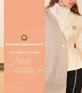 Detailed view of matte gold flower brooch with pearl accent on elegant beige blazer