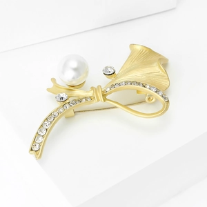 Détail d'une broche feuille de ginkgo dorée mate avec perle et strass scintillants