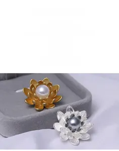 Close-up of matte gold and silver floral brooches with pearl center on silk