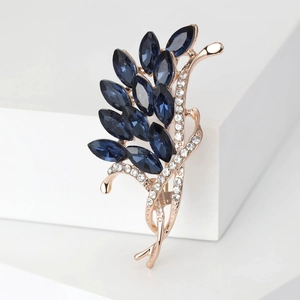 Close-up of rose gold floral brooch with deep blue marquise crystals and clear rhinestones