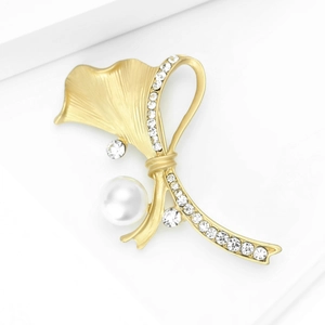 Détail d'une broche feuille de ginkgo en or mat avec perle blanche et strass étincelants
