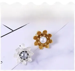 Detail view of matte gold and silver floral brooches with elegant pearl centers