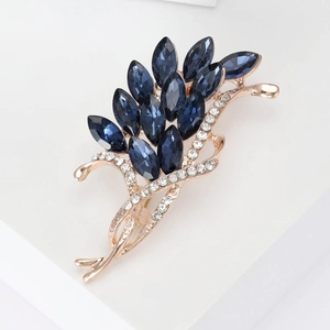 Detailed view of wheat-shaped rose gold brooch with dark blue crystals and zircons