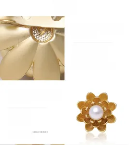 Macro shot of matte gold floral brooch petal with brushed texture and central pearl detail
