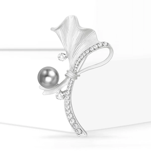 Broche feuille de ginkgo en argent mat avec perle grise et cristaux sur fond blanc