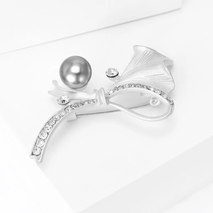 Détail de la broche argentée mate avec perle gris foncé et strass pavés brillants