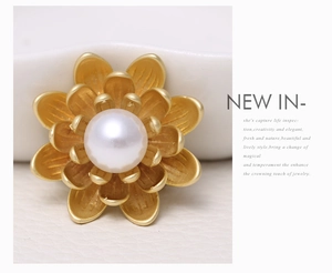 Detail view of a matte gold floral brooch with a large white pearl and layered petals