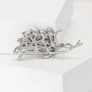 Detailed back view of silver hollowed leaf brooch with secure pin clasp and blue crystals
