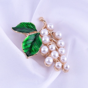 Détail d'une broche en forme de raisin avec feuilles d'émail vert et perles blanches