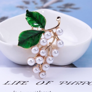 Macro d'une broche raisin avec feuilles en émail vert et perles sur monture dorée