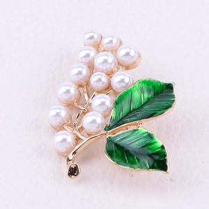 Détail de la broche muguet avec perles blanches et émail vert sur métal doré