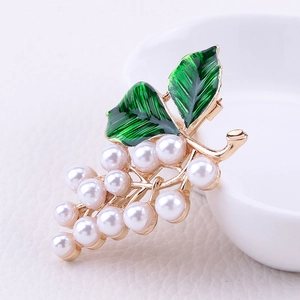 Macro d'une élégante broche de raisin avec feuilles en émail vert et perles nacrées