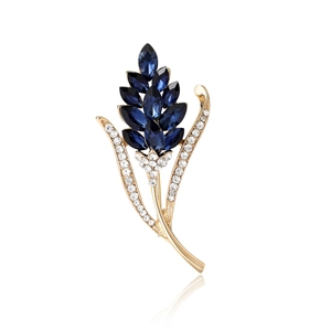 Eleganter Ähren-Brosche in Gold mit blauen Edelsteinen und weißen Kristallen vor weißem Grund