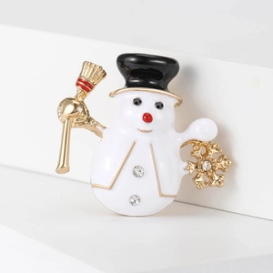 Detailed macro view of enamel snowman brooch with rhinestone accents and gold broom