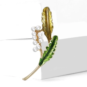Élégante broche feuille dorée avec émail vert et perles blanches sur cubes blancs