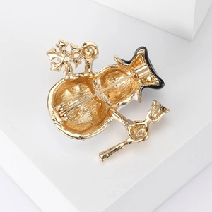 Back view of gold plated snowman brooch with metal pin clasp on white geometric block