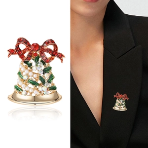 Broche cloche de Noël avec nœud en strass rouge et feuilles vertes sur fond blanc et mannequin