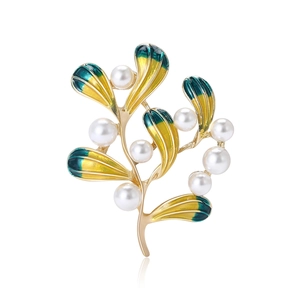 Elegante spilla a ramo dorato con foglie di smalto verde e perle bianche su sfondo bianco