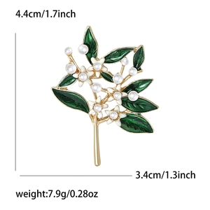 Elegant gold metal flower brooch with green enamel leaves and white pearl center