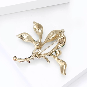 Detailed macro view of the gold-tone alloy back and safety pin clasp of the plant brooch