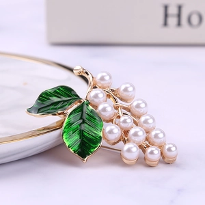 Broche raisin dorée avec feuilles en émail vert et perles blanches sur porcelaine blanche
