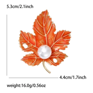 Maple leaf brooch with orange enamel finish, white pearl center and gold accents