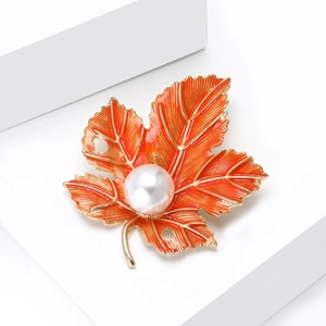Golden maple leaf brooch with orange enamel finish and a white center pearl accent