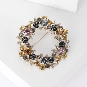 Dettaglio della spilla a ghirlanda in argento con strass colorati e rose nere