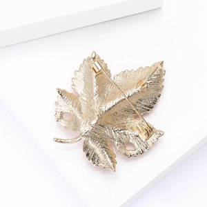 Detailed back view of golden maple leaf brooch showing secure pin clasp and metal texture