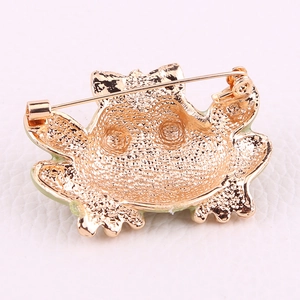 Detailed view of the frog brooch back featuring golden texture and safety pin clasp