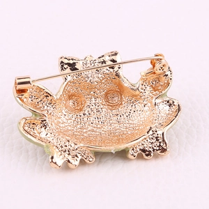 Golden crab-shaped alloy brooch with textured back and pin clasp on white background