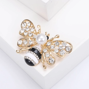 Gros plan de la broche abeille avec diamants incrustés et perle blanche sur socle