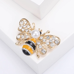 Détail macro d'une broche abeille avec cristaux brillants, perle et émail jaune